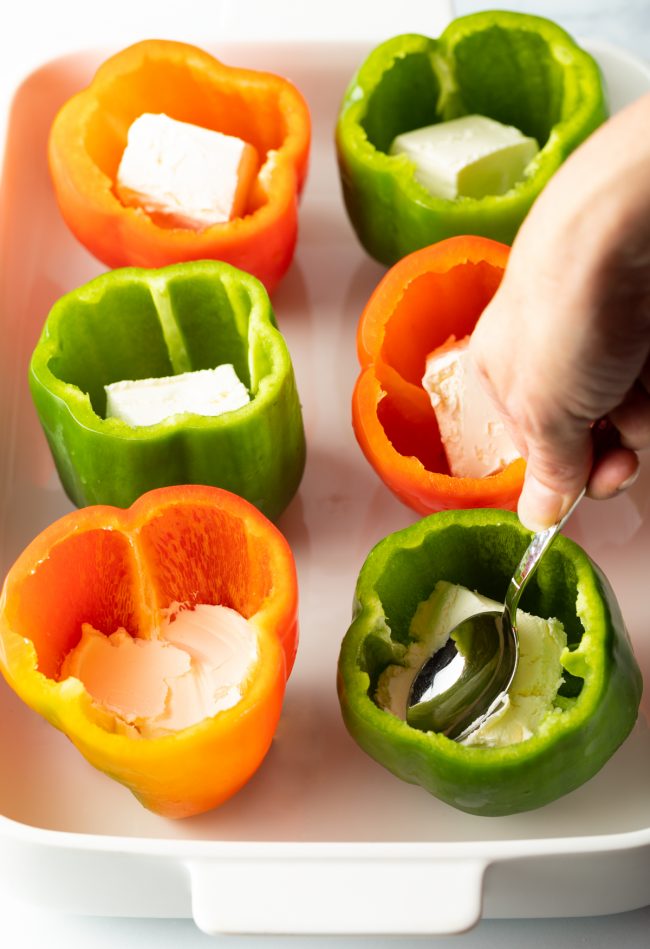 use a spoon to press cream cheese into each pepper cavity