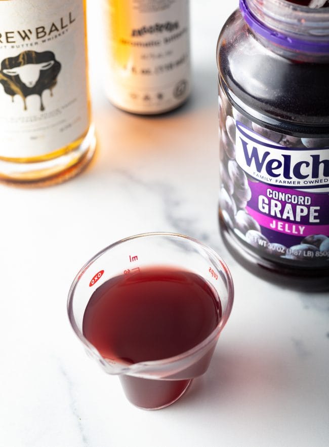 Top view grape jelly simple syrup in a glass measuring cup.
