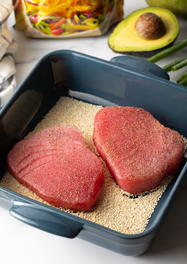 close view two tuna steaks in a pan with sesame seeds