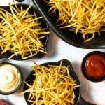 Crispy French fries served with ketchup and mayonnaise in black bowls.