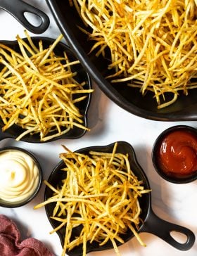 Crispy French fries served with ketchup and mayonnaise in black bowls.