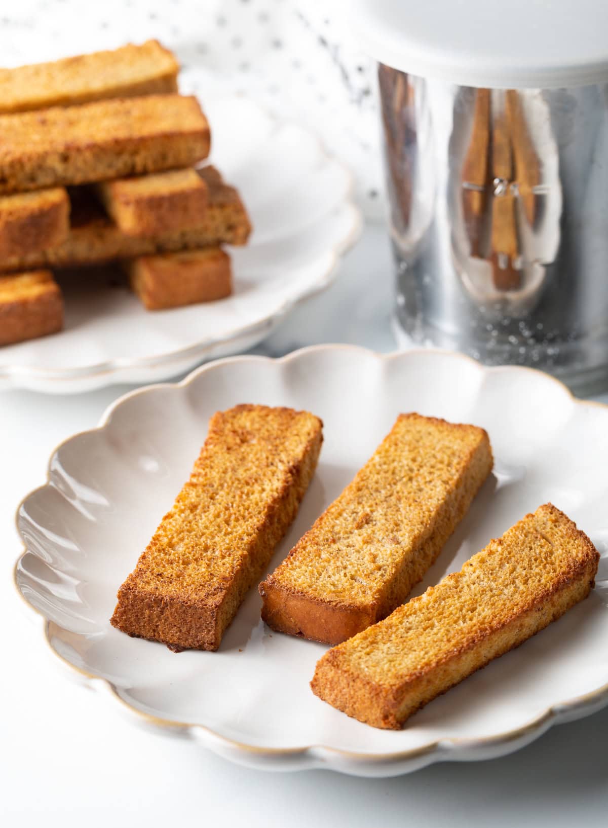 Three air fryer French toast sticks are sitting on a white plate.