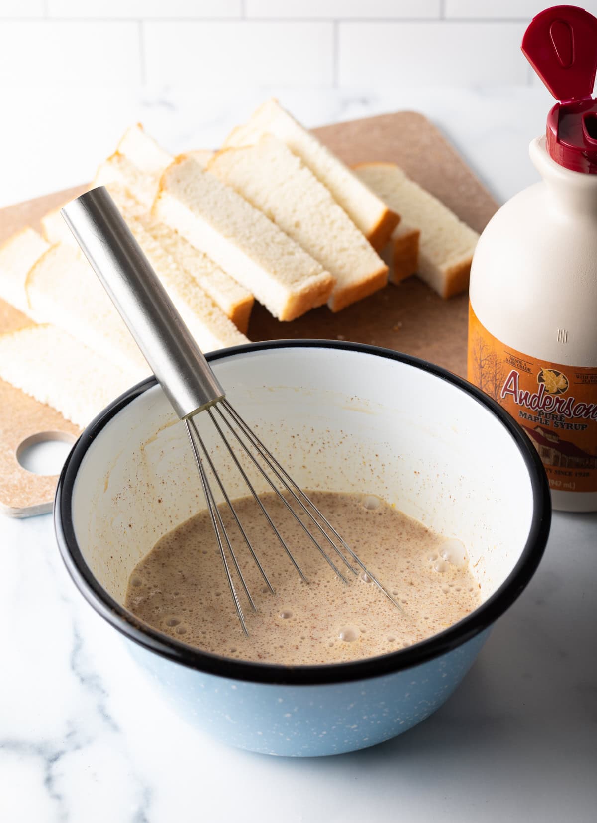 An egg and cream mixture is being whisked in a white bowl.