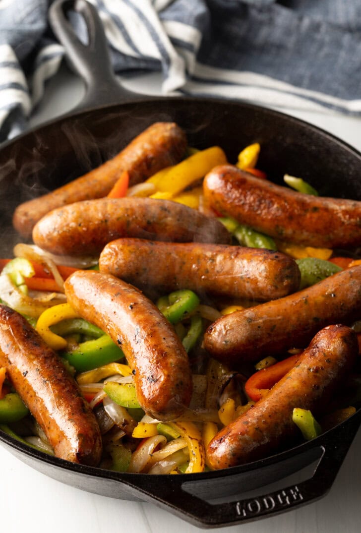Skillet filled with sauteed veggies and sausages.