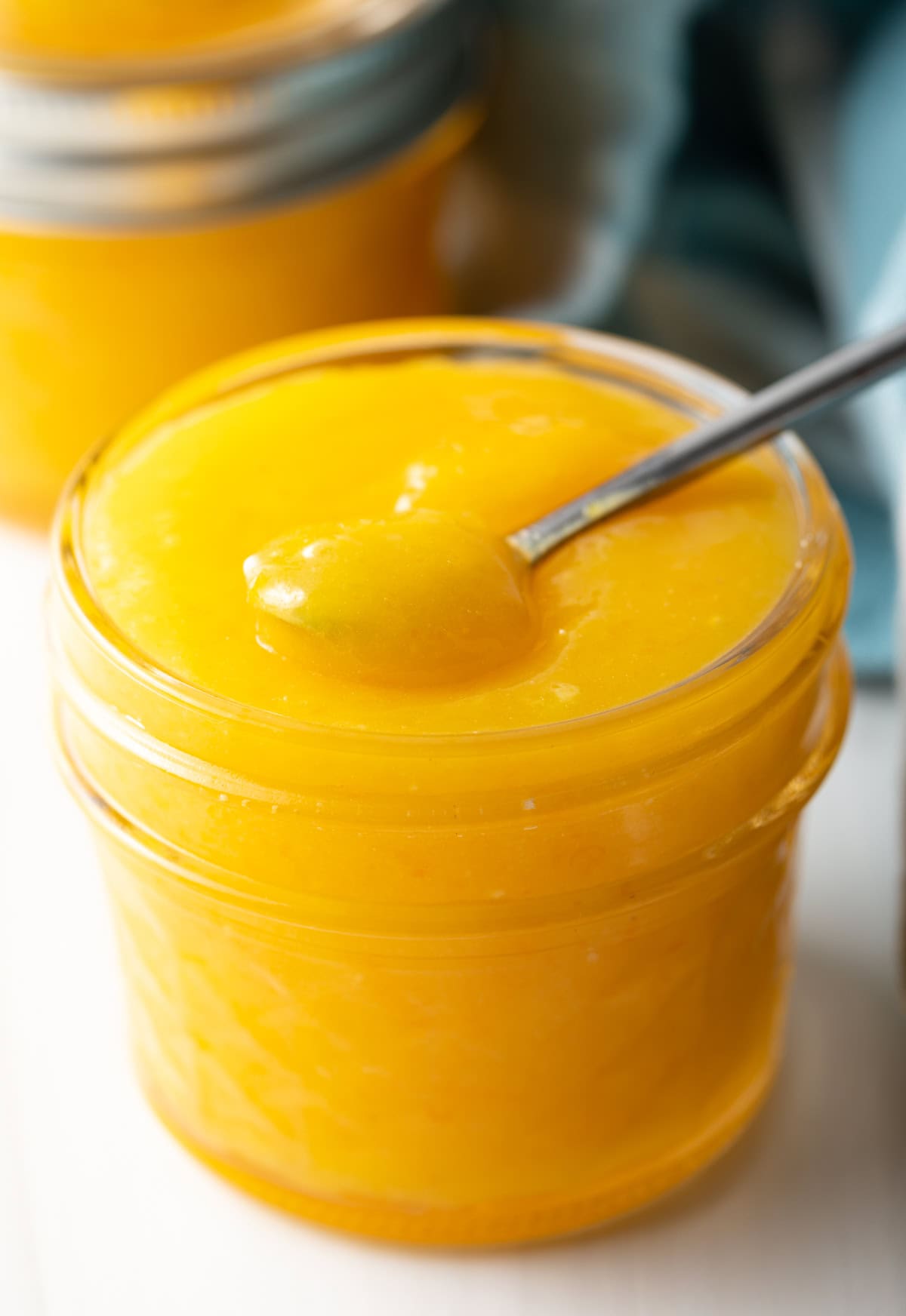 Finished jar of homemade orange curd with little spoon.