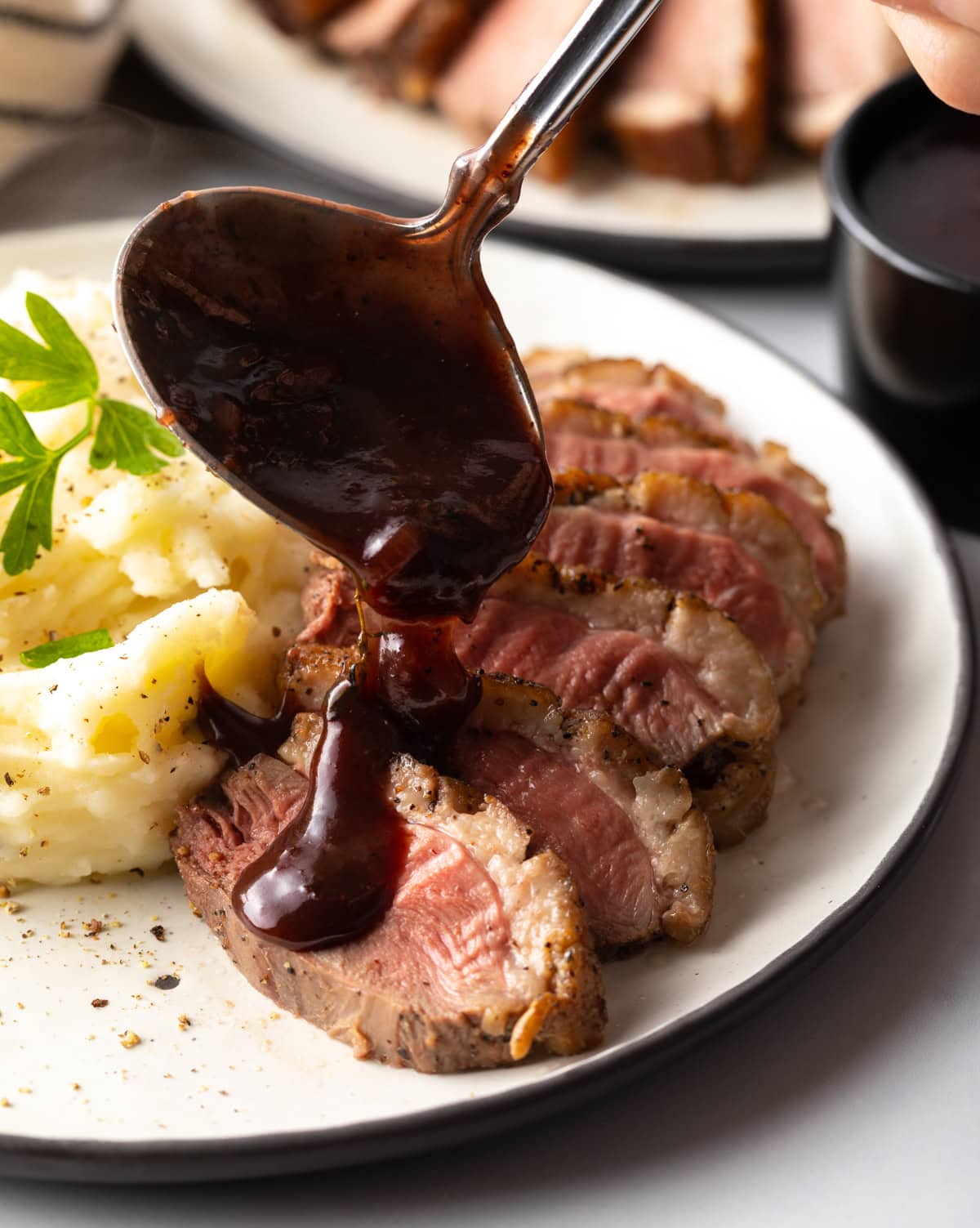 BlackBerry sauce being poured over sliced duck breast. 