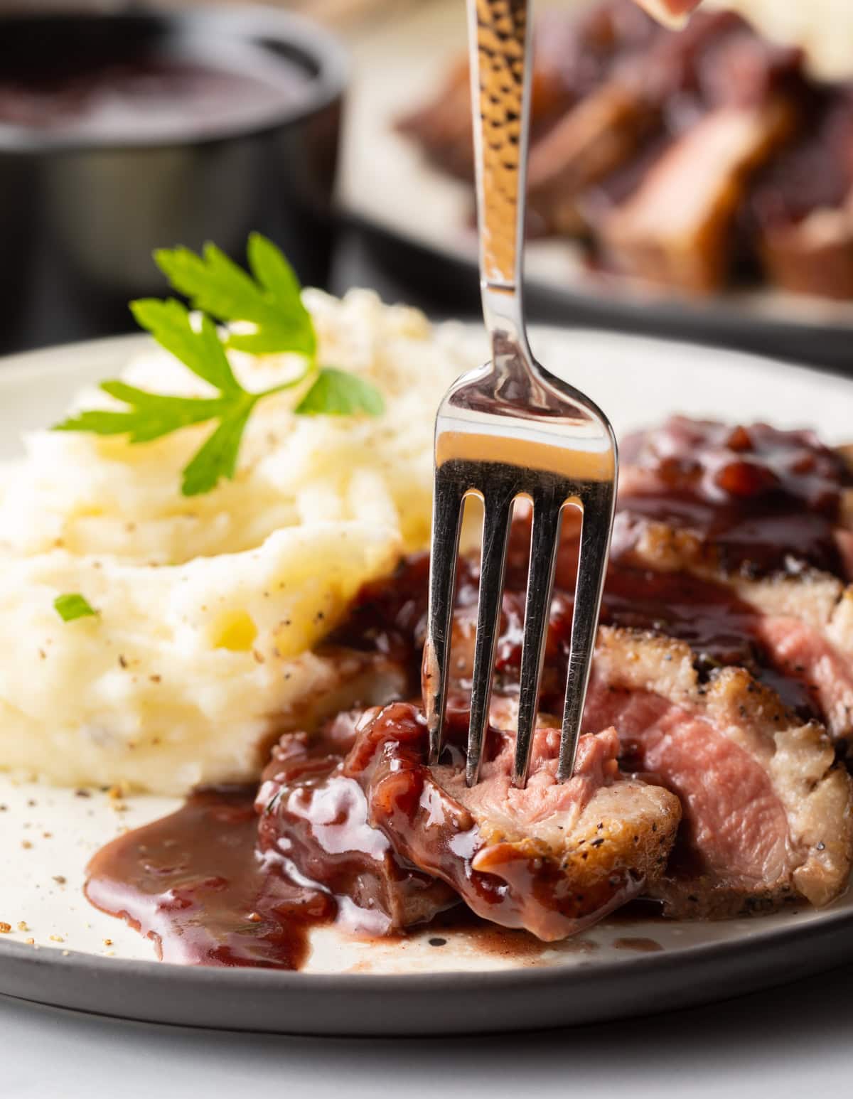 Fork biting into piece of duck. 