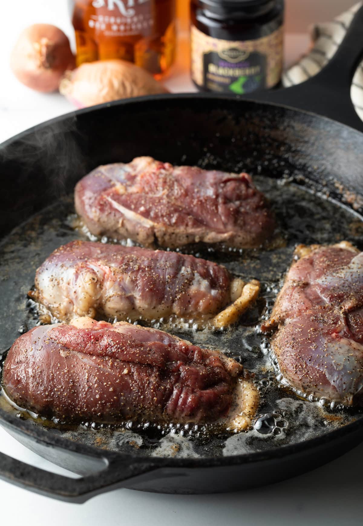 Duck breast being seared skin side down in pan.