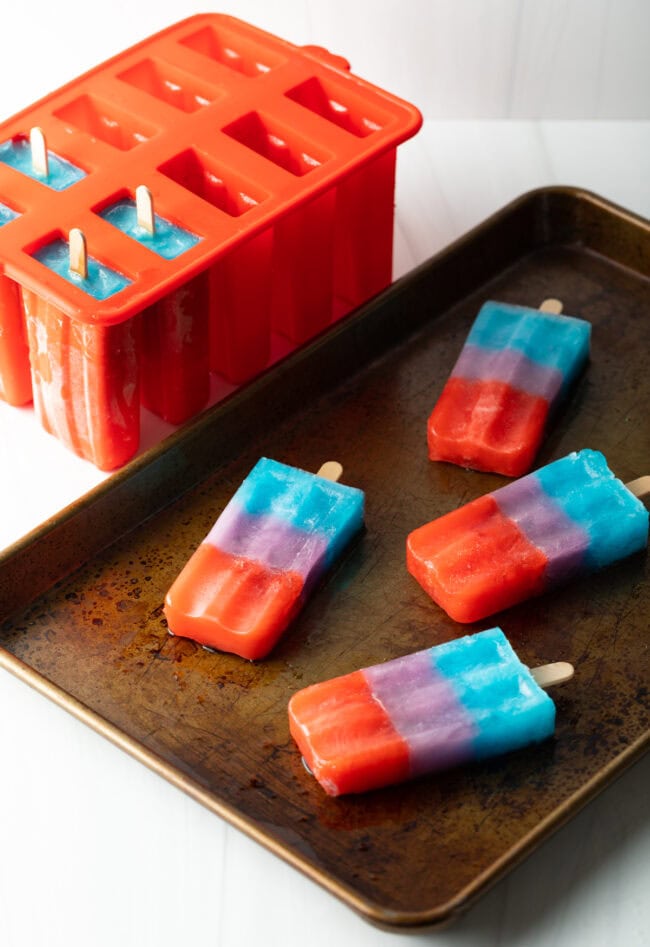 Popsicles on a baking sheet with silicon mold in the background. 