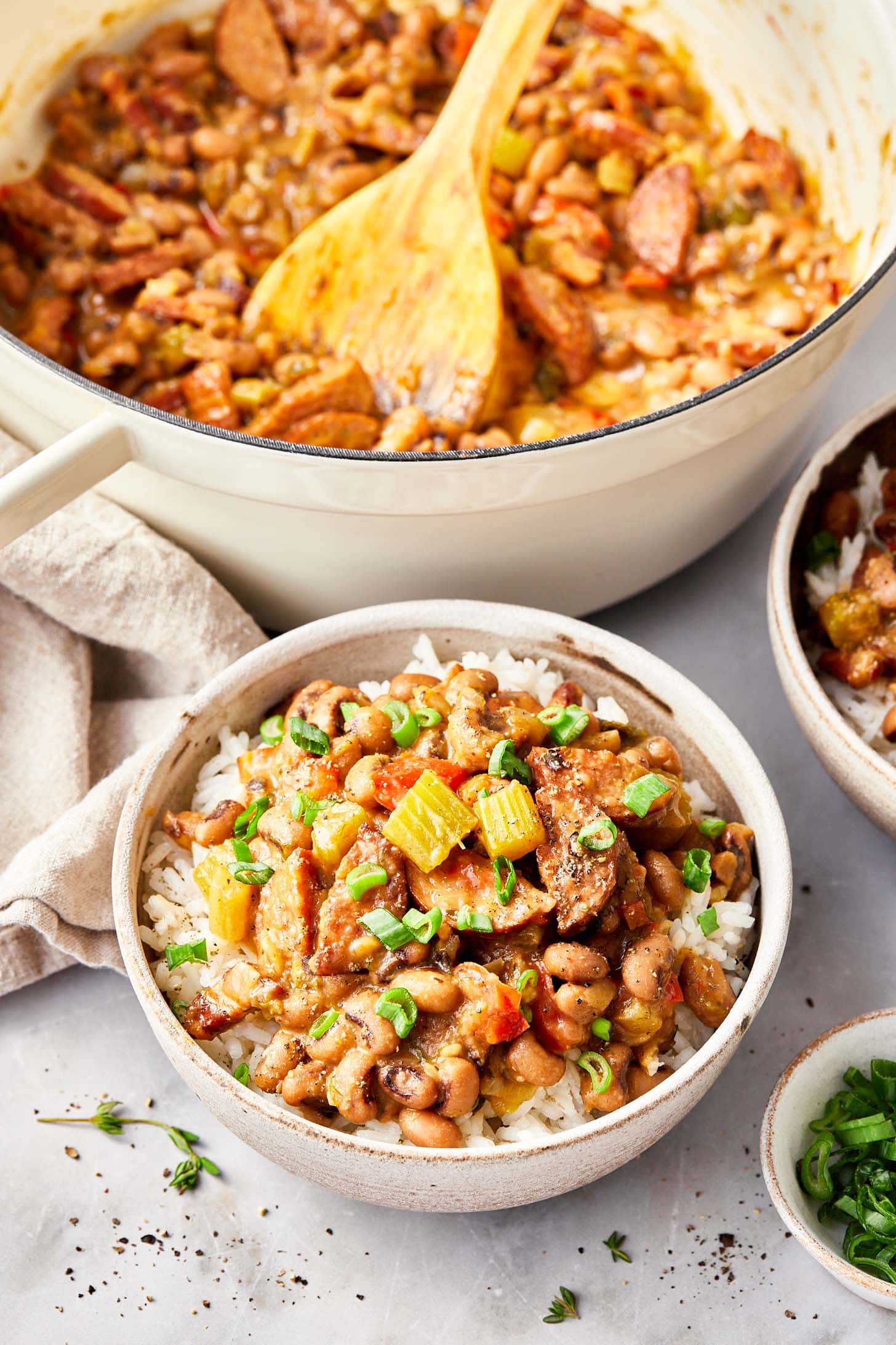 Overhead view of pot full of hoppin john with a closeup of ready to eat bowl of hoppin john served over white rice.