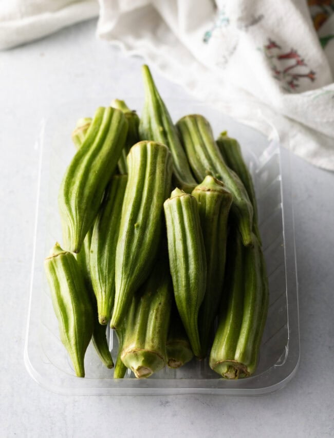 Raw whole okra in a plastic container