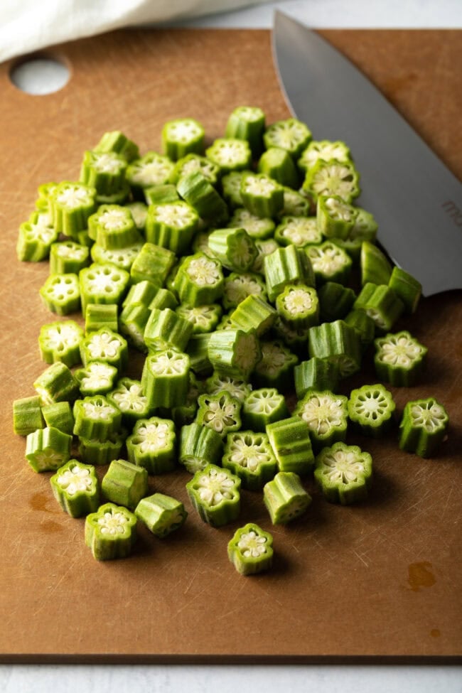 Sliced okra on a cutting board with knife.