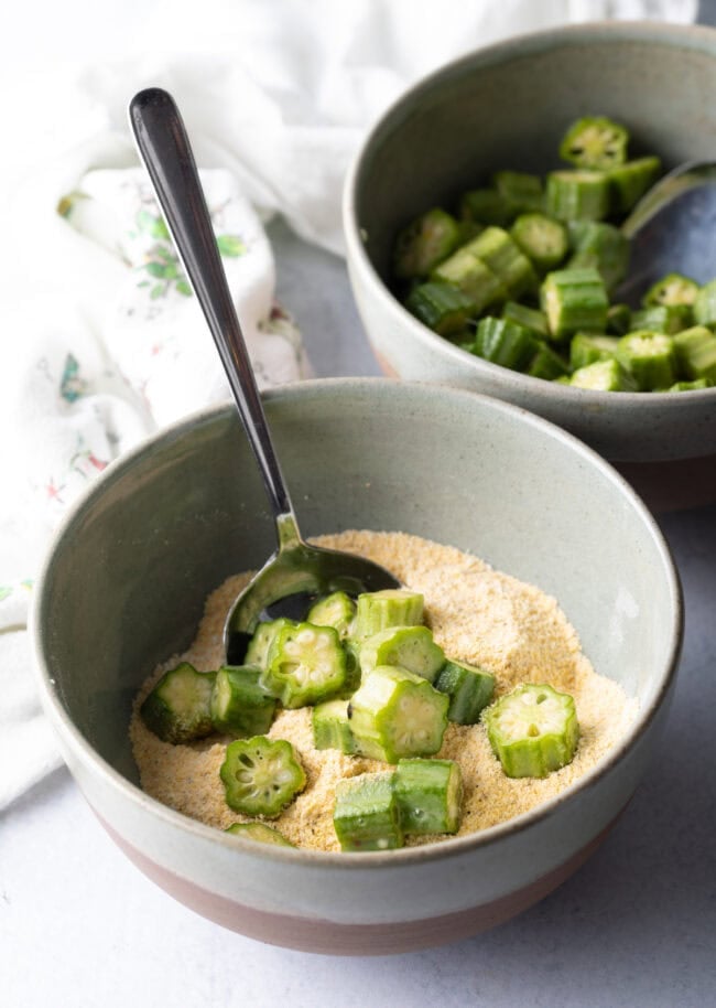 Adding okra slices to breading mixture.