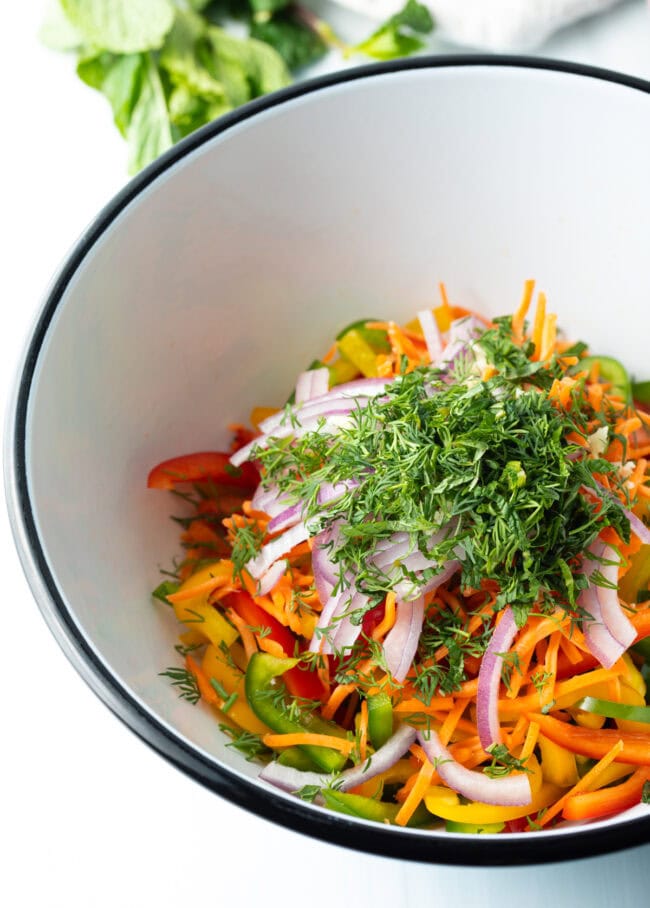 Sliced ingredients topped off with chopped herbs in a bowl. 