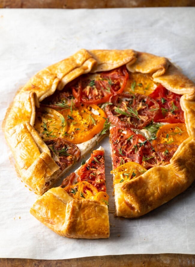 Savory crostata on baking paper, one slice moved to the side.