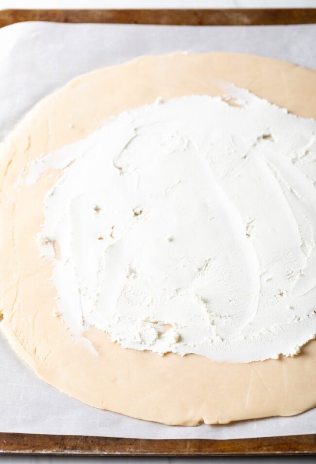 Soft goat cheese spread on rolled out pie crust.