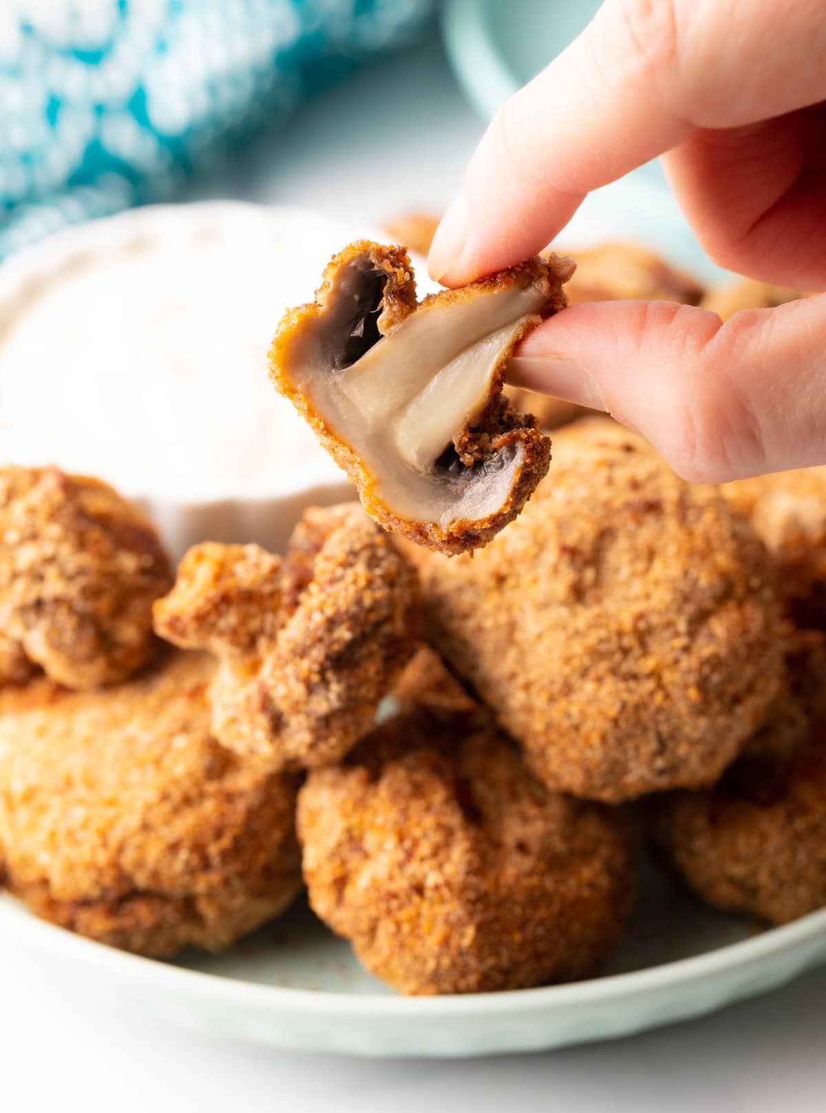 Hand holding mushrooms bitten in half, showing inside to camera.