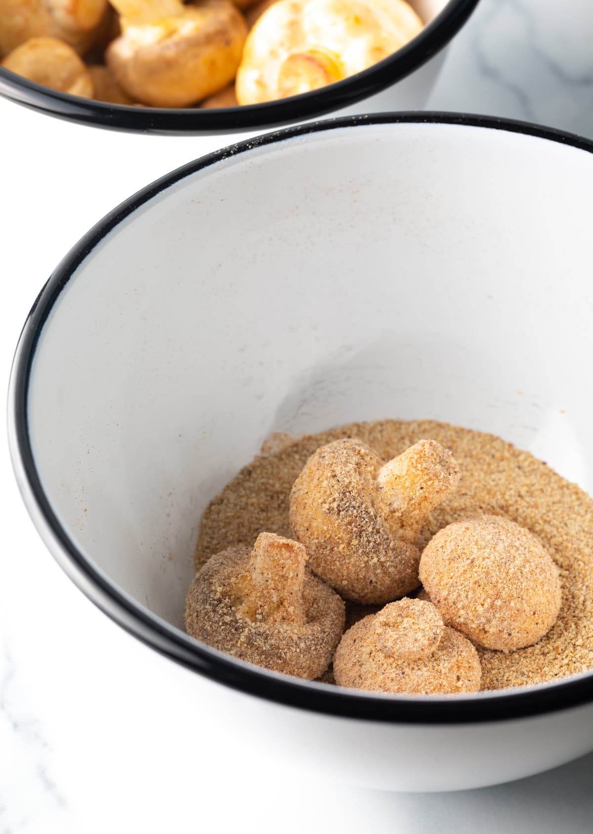 Raw mushrooms in a breading mixture.