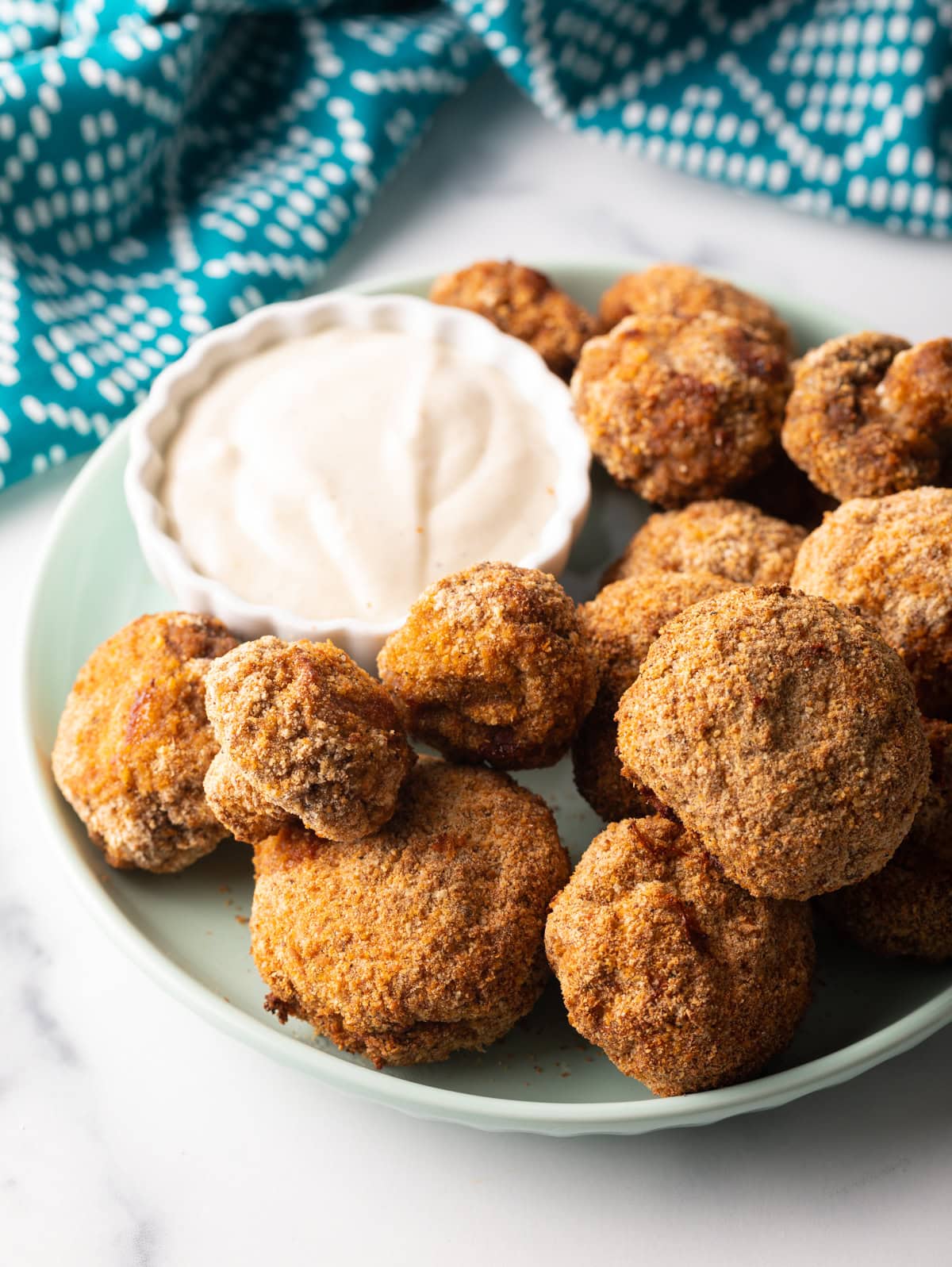 Air fryer mushrooms on a plate with ramekin of sauce.