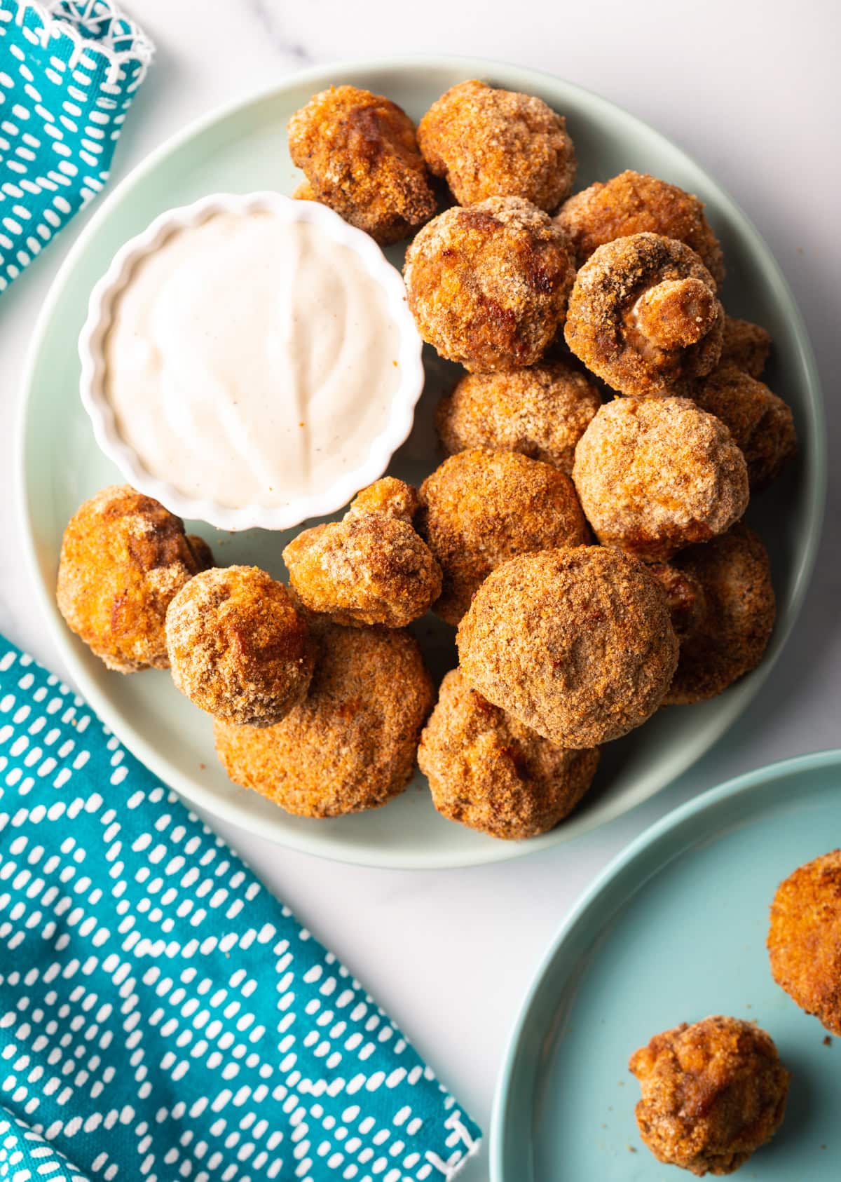 Plate of air fryer mushrooms top down, with ramekin of sauce.