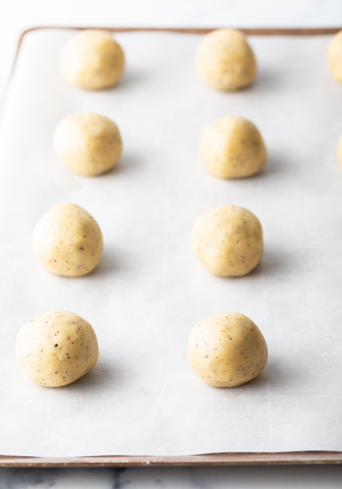 8 balls of cookie dough on a baking sheet with parchment paper.