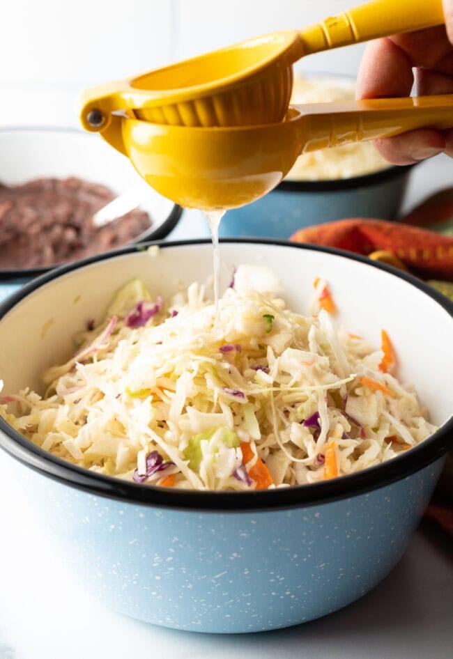 Squeezing lemon into bowl of coleslaw.