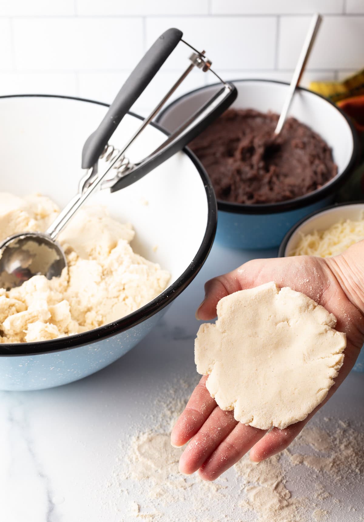 Hand holding flattened dough.