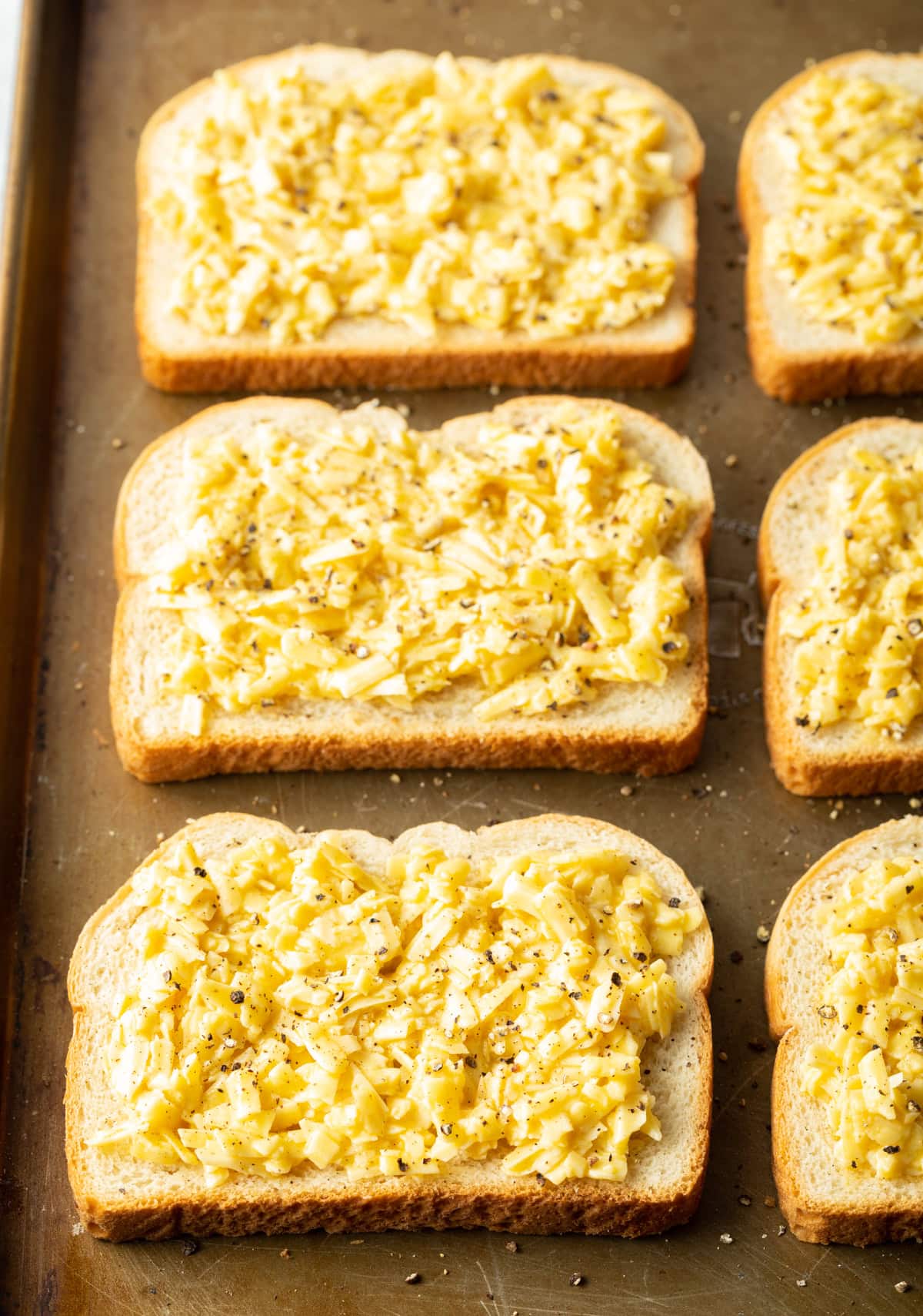 6 pieces of bread on a baking sheet covered with the egg mixture and shredded cheese.