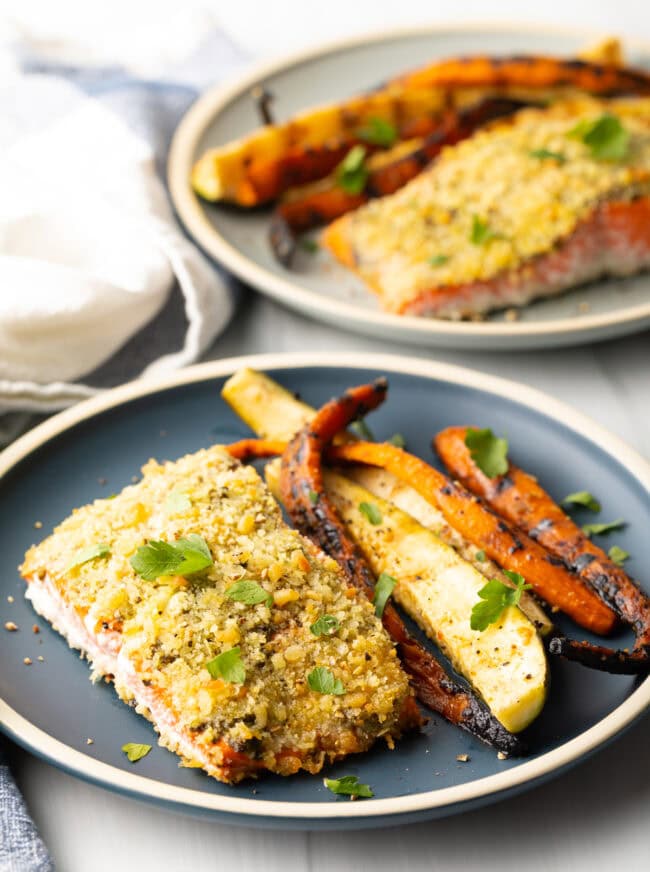 Bake pesto salmon at 400 degrees, serve on a plate with grilled veggies.