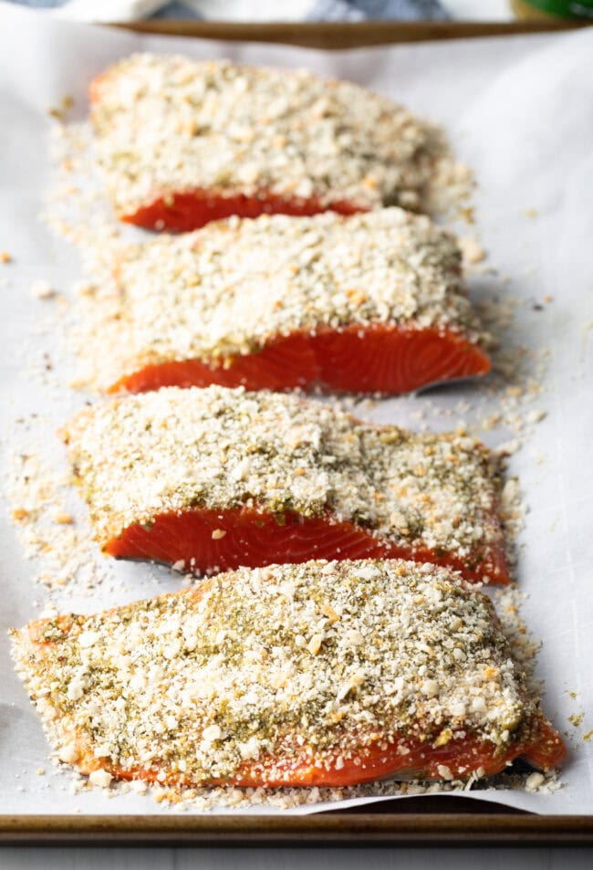 4 raw pieces of pesto salmon coated with Panko breadcrumbs.