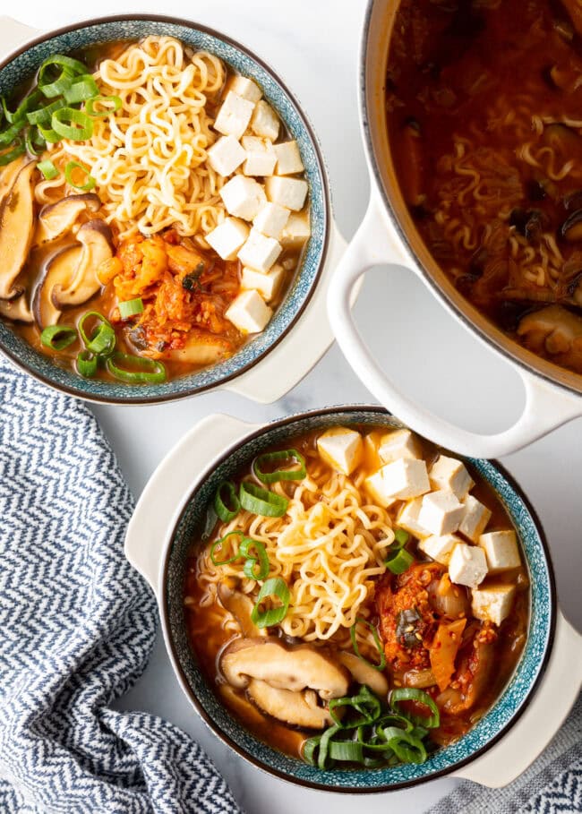 Top down view two bowls of vegetarian and vegan ramen noodle soup with kimchi.