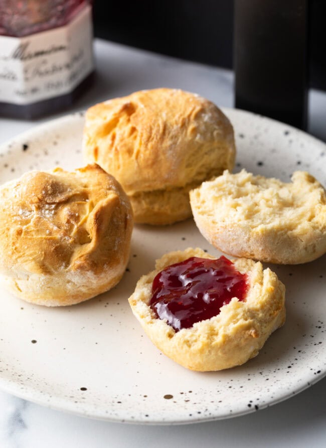 Plate with two air fryer biscuits, one opened with jelly on half.