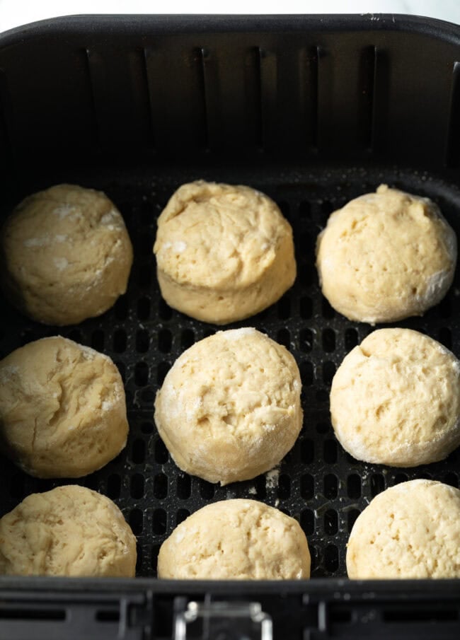 Top down 9 biscuits in air fryer basket, unbaked.