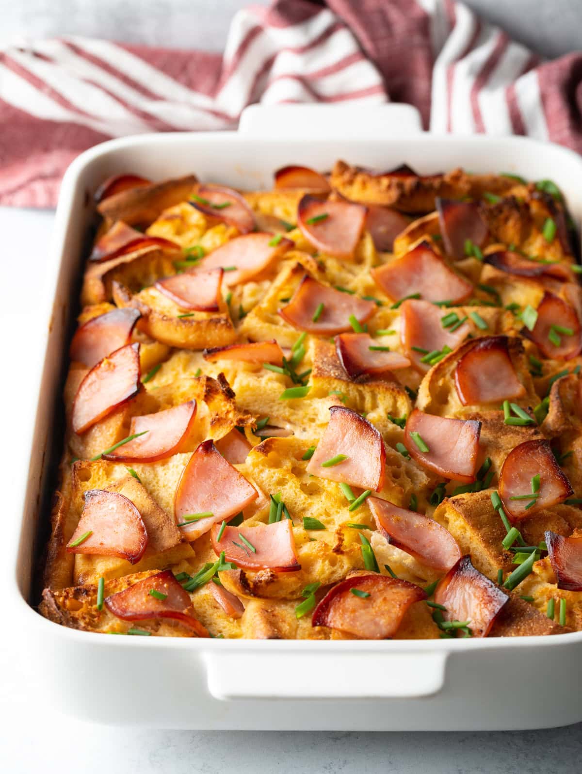 Baked eggs benedict breakfast casserole in a white baking pan.