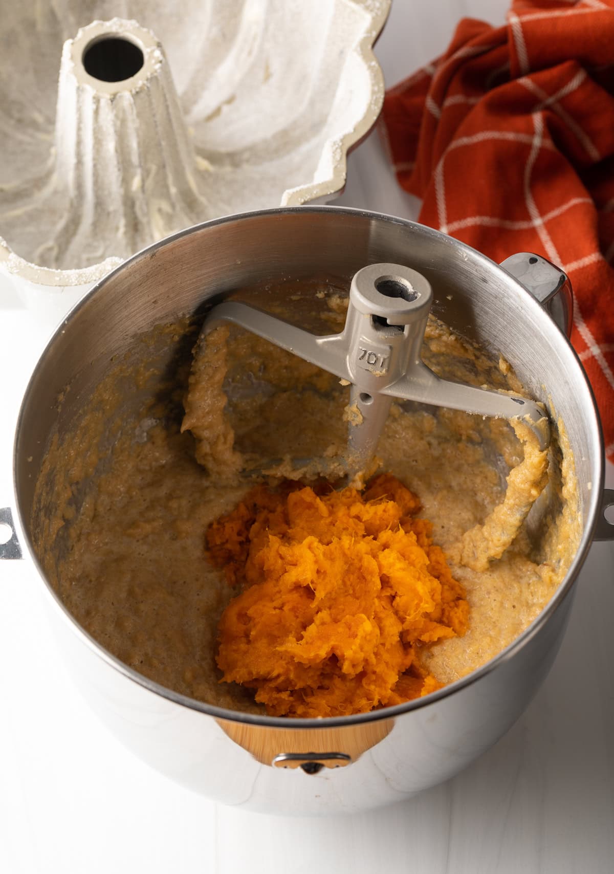 Cake batter with potato mash in a mixing bowl with paddle.