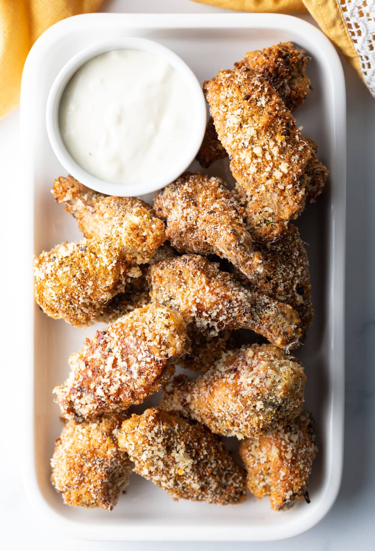 Top down view crunchy parmesan garlic wings and ramekin of white dressing.
