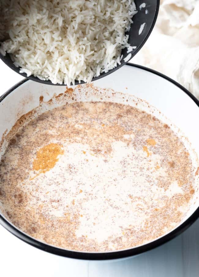 Adding cooked white rice to the cream mixture in the bowl bowl.
