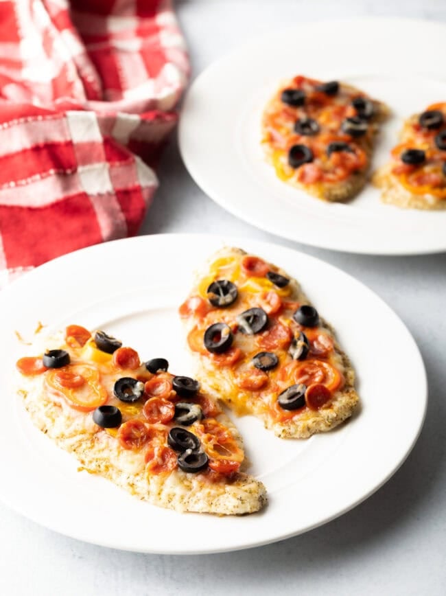 Plates of keto chicken pizza crust topped with cheese and veggies.