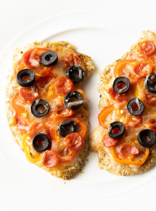 Two slices of chicken crust pizza with toppings on a white plate.