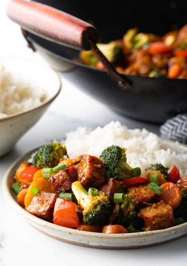 Close view of tempeh stir fry veggie bowl with white rice.