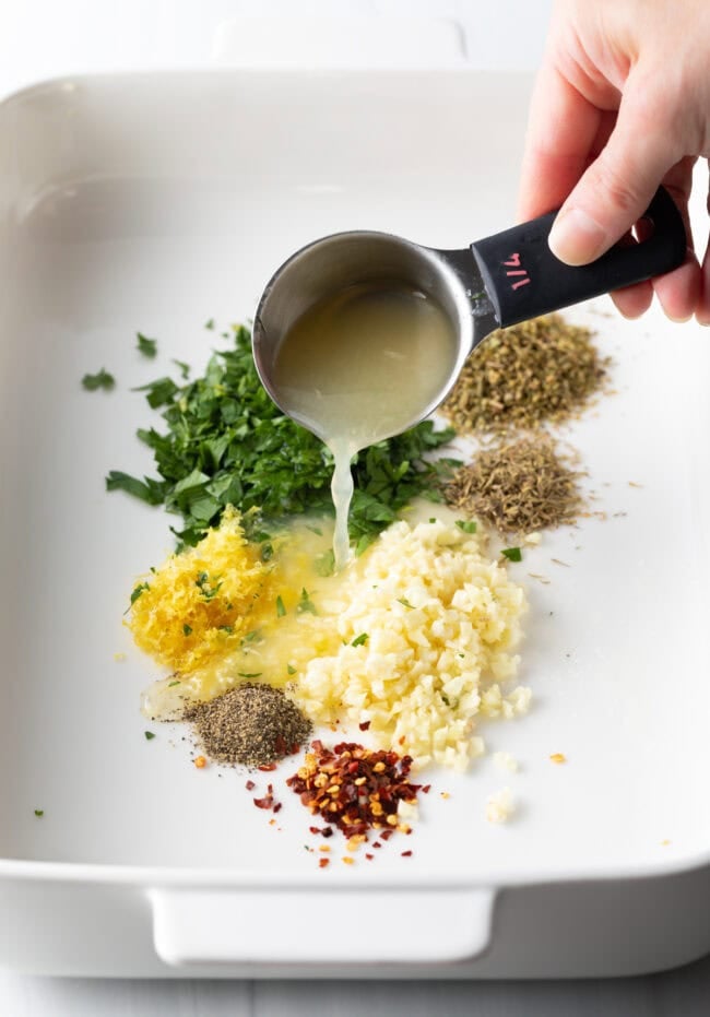 Pouring lemon juice in pans with aromatics and spices.