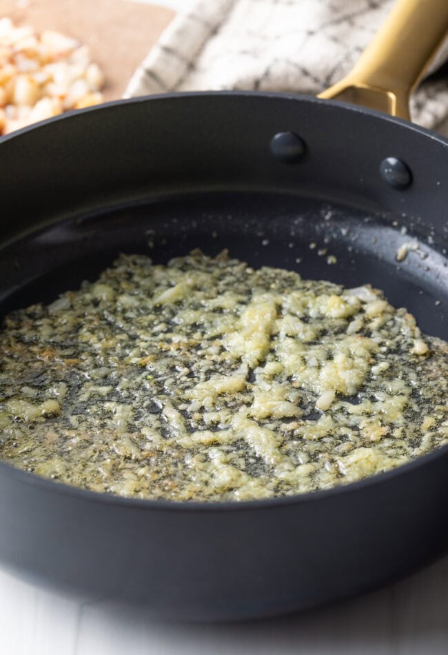 Garlic being sautéed in a pan with butter. 