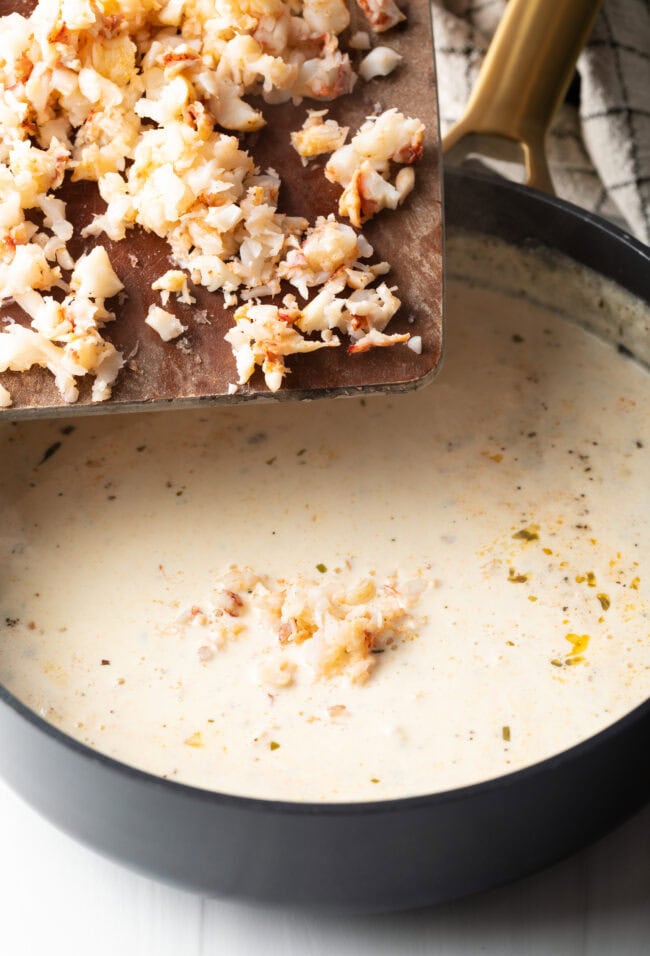 Lobster added to a creamy sauce in a pan. 