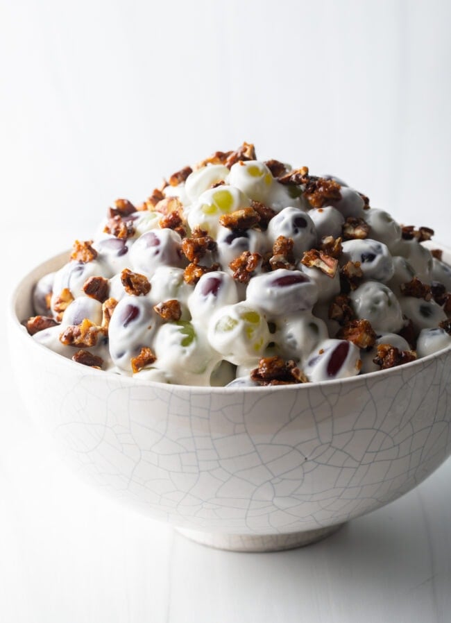 Side view of creamy salad with grapes in a white bowl.