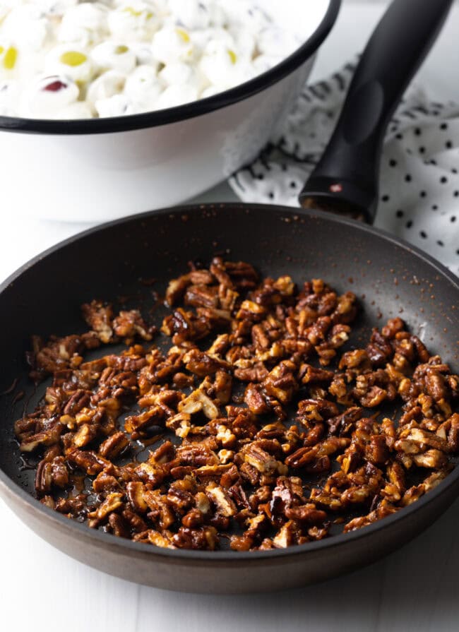 Toasting pecans in a black nonstick skiller.