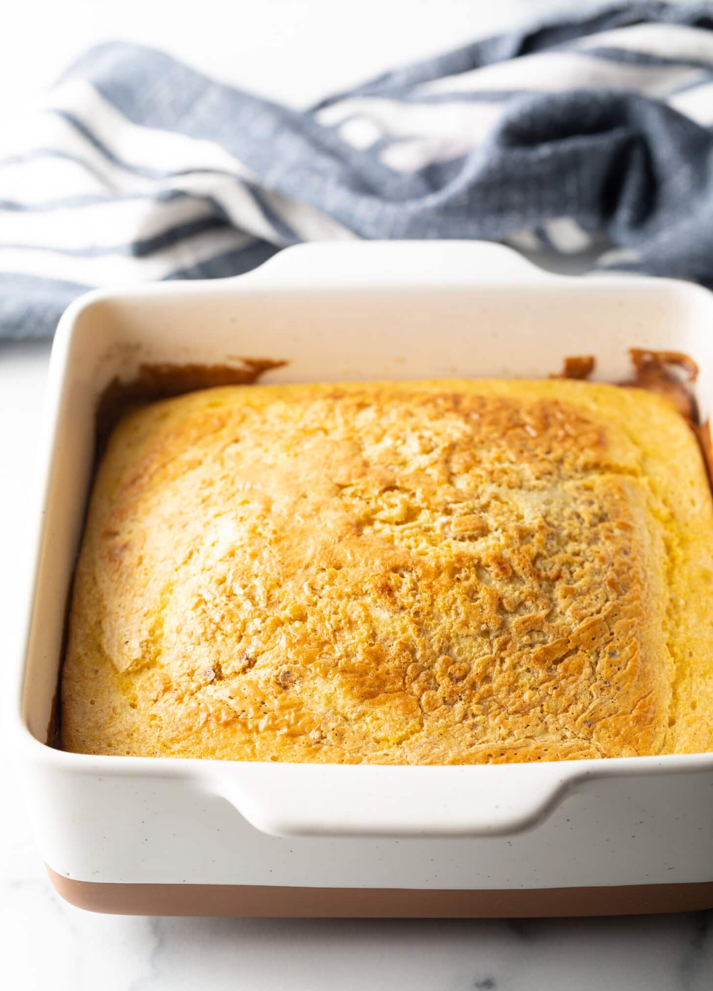 Baked corn spoon bread in a white square dish.