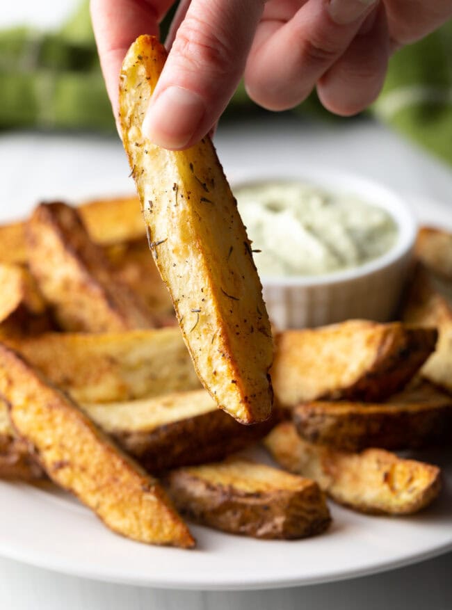 Hand holding a thick wedge from the air fryer.