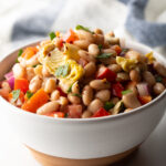 White bowl brimming with white bean and artichoke salad.