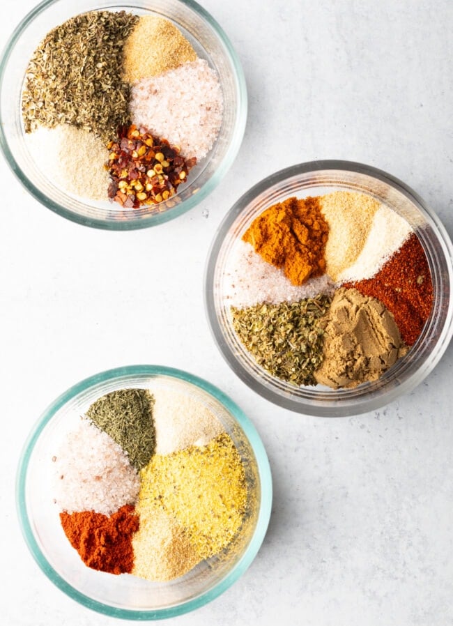 Top down view three bowls, each with a different blend of chicken seasoning.