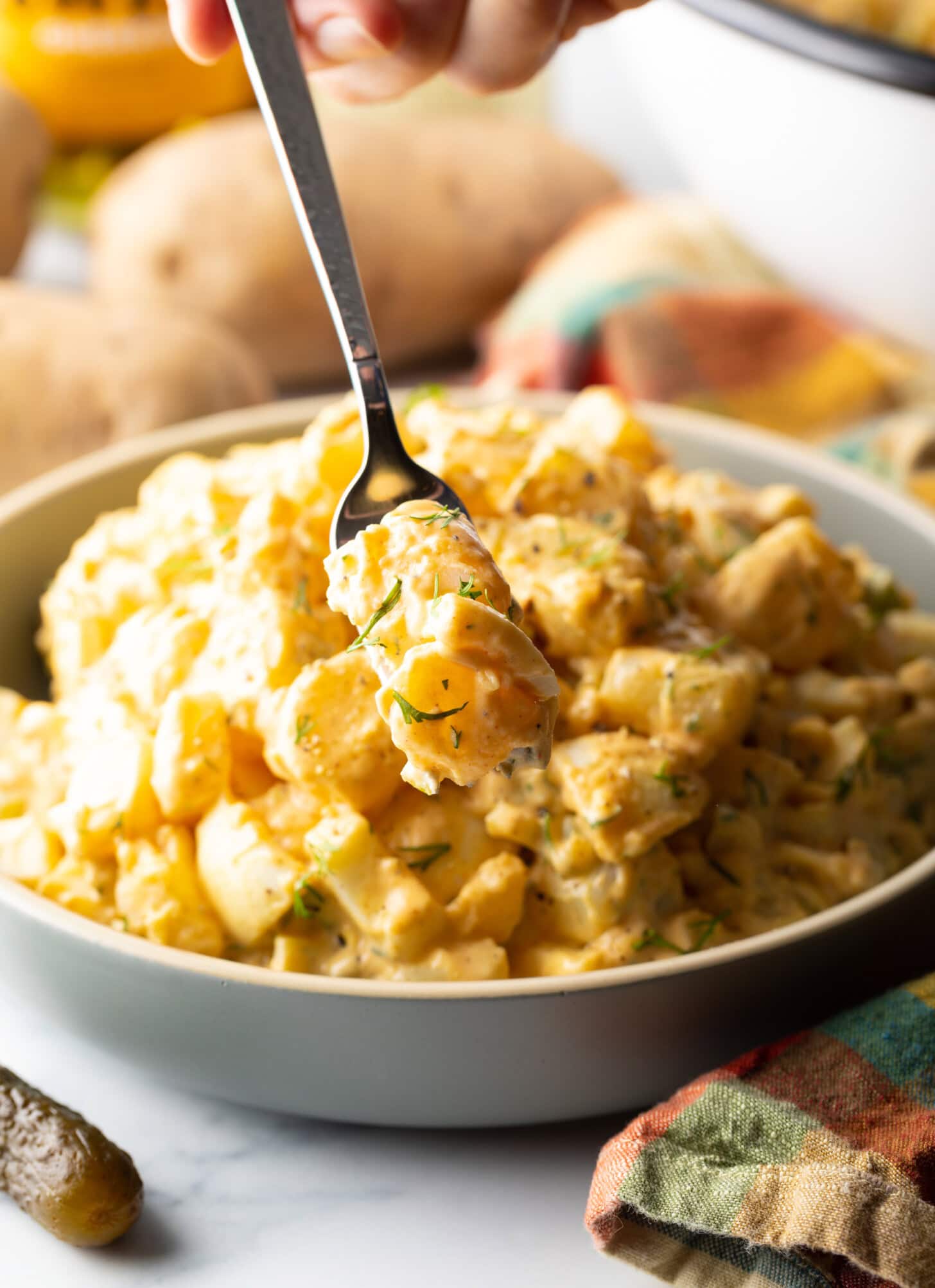 Metal fork getting a bite of deviled egg potato salad.
